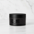 Black container of STMNT Shine Paste on a white background