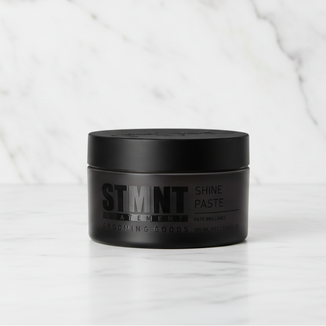 Black container of STMNT Shine Paste on a white background